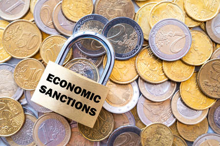 Padlock with "economic sanctions" text next to money. Economic sanctions, economic retaliation against the war.の写真素材