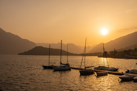 Tremezzina, the small harbor with boats, and the tip of Balbianello in the background, at sunset.の写真素材