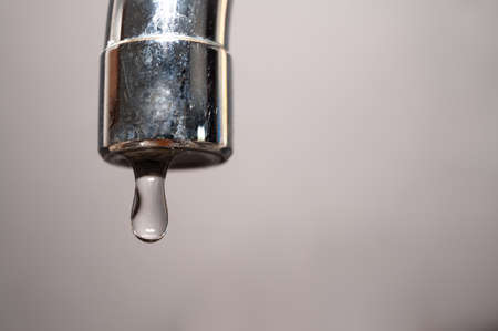 Tap from which drops of water flow. Drought, shortage, rationing and proper use of water.の写真素材
