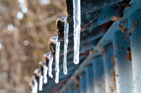 Ice candles protruding from a roof. Cold wave and winter temperatures.の素材 [FY310198290889]