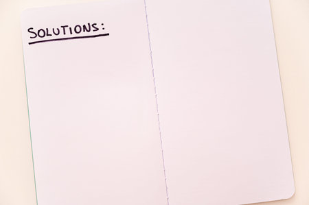 Blank notebook page, with the writing Solutions, and marker next to it. Solutions, problems and...