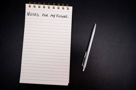 Lined notepad, blank page, text "notes for my future", on black surface, with pen beside. template.の写真素材