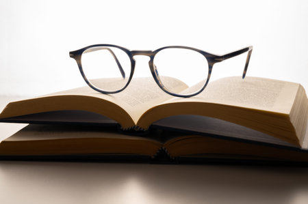Glasses on the open book on a white background close-up. Viewing, reading, studying.