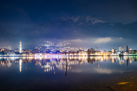 The city of Lecco, with its lakeside promenade and its buildings, photographed in the evening in winter.の写真素材
