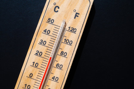 Thermometer on dark surface. Rising temperatures and global warming.