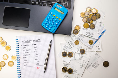 Savings, finances, economy, business and home concept - close up of calculator, coins and notebook on tableの写真素材