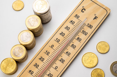 Room thermometer and stacks of coins and money. Space heating costs.の写真素材