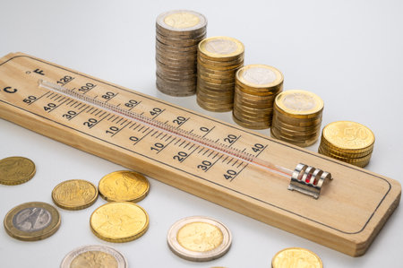 Room thermometer and stacks of coins and money. Space heating costs.の写真素材