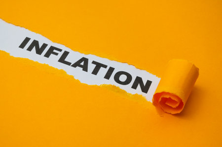 White surface, with the word Inflation in black, underneath torn and rolled yellow cardboard.の写真素材