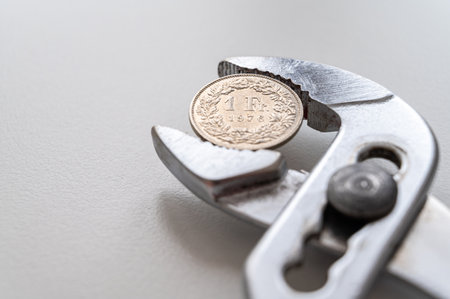 Pliers holding Swiss Franc coin. Financial pressures and squeezes on the currency.の写真素材