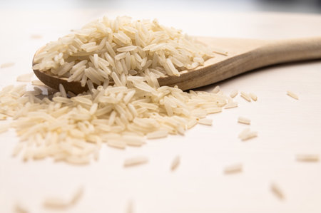 Raw basmati rice, in wooden ladle, on light wooden surface.の写真素材