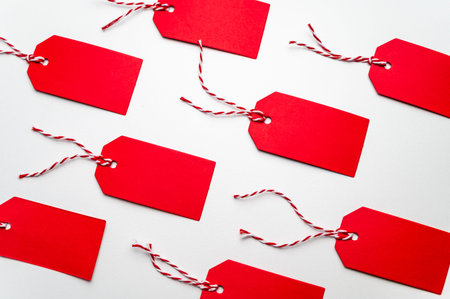 Red tags, with a string, on a white surface.