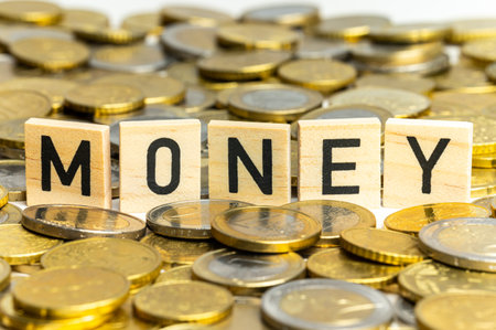 Wooden squares that spell out the word Money, on top of a surface of euro coins.の写真素材