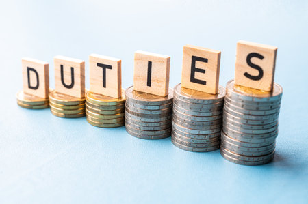 Stacks of coins of increasing height and wooden tiles that spell out the word duties. Consequences of new duties.の写真素材