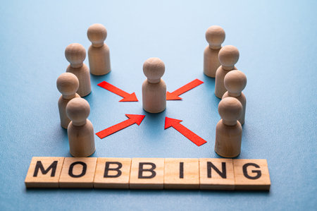 Concept of mobbing, exclusion and psychological violence in the workplace. Abstract representation, with wooden pawns, of a person targeted by other people.の写真素材