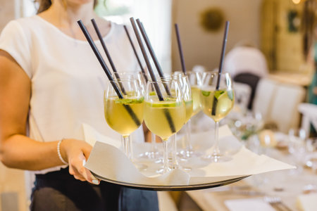 Close up of female waiter holding a tray with glasses of mojito cocktail