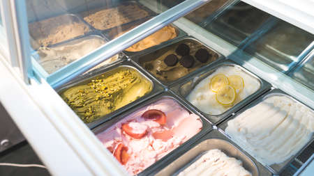 different kinds of ice cream scoop at cafe, Italian gelato with chocolate, pistachio, lemon, vanilla, scotch and tomato flavours. Soft focus, blurred background, film noiseの写真素材