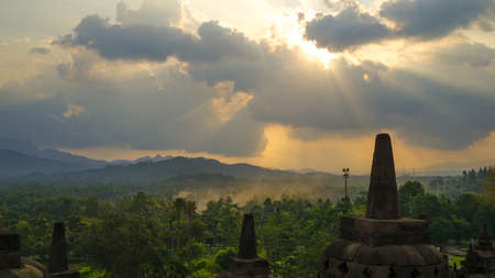 Glorious sunset at Borobudur Temple in East Java, Indonesia. Blue and orange sky over the hills, green jungles and stupa, travel destination.の写真素材