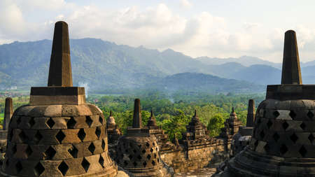 Glorious sunset at Borobudur Temple in East Java, Indonesia. Blue and orange sky over the hills, green jungles and stupa, travel destination,の写真素材