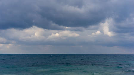 dramatic clouds in the sky over the sea, before the rain, heavy weather, grey clouds, turquoise ocean, soft focus, film noiseの写真素材