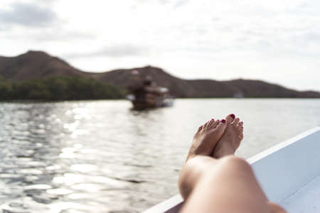 Female feet on the yacht in summer. Sunbathing on the boat on the sea. Relaxing and travel concept. Single woman resting on the cruise. Luxury and freedom lifestyle. Woman on the boat in the eveningの写真素材