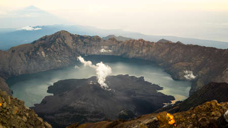 Pink sunrise with triangle shadow of the peak, landscape with clouds in the morning, beautiful volcano Rinjani Gurung at Lombok Island, Indonesia. Small lake in the mountains. 3726m peak Mount Rinjaniの写真素材