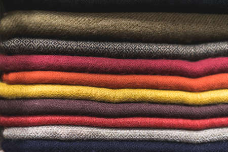 close up of colorful fabric,  a pile of cashmere textile, stack of colorful clothes, pile of clothes, dark colours of scarfsの写真素材