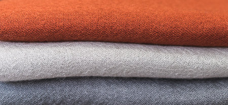 orange grey white wool sweater, close up of colorful fabric,  a pile of cashmere textile, stack of...