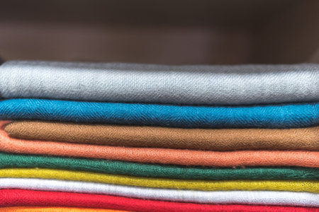 folded scarfs on the shelf, close up of colourful fabric, a pile of cashmere textile, stack of...