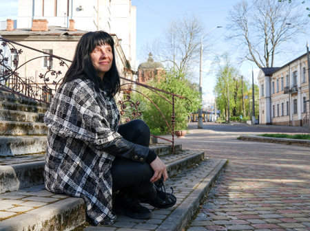 A woman sitting on the steps. portrait of a woman. Happy smiling Caucasian woman with black medium...