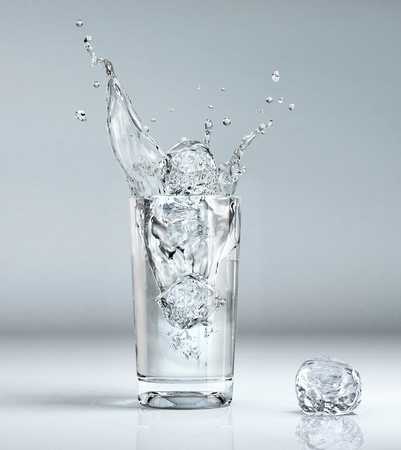 ice cube splashing into a glass full of waterの写真素材