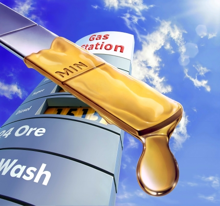 Close up of an engine dipstick, with an oil drop at the edge of it  Blue sky and fluffy clouds and a gas station sign in the background の写真素材