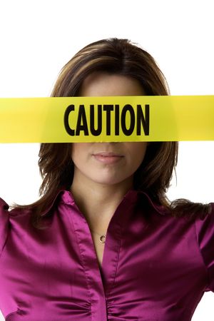 Brunette holding yellow caution tape over eyes and noseの写真素材