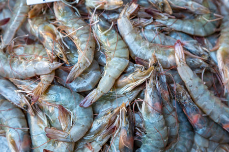 Looking down on raw uncooked prawns for sale, on a market stall