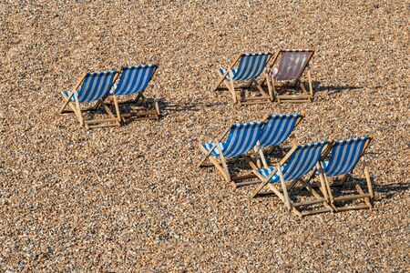 Looking down on vacant striped deckchairs on a pebble beachの写真素材