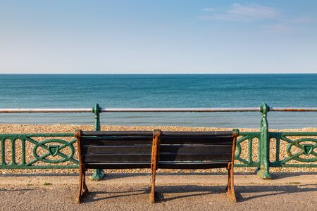An empty bench on the promenade in Brighton, on a sunny summer's morningの写真素材