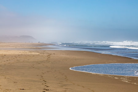 The vast sandy Ocean Beach in San Francisco, with a mist in the distance