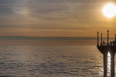 Looking at silhouettes on the end of the pier at sunset, at Manhattan Beach, Californiaの写真素材