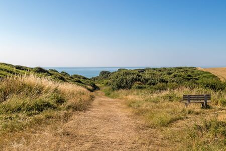 A bench with a view, and a pathway leading to the sea, at Hope Gap in Sussexの写真素材
