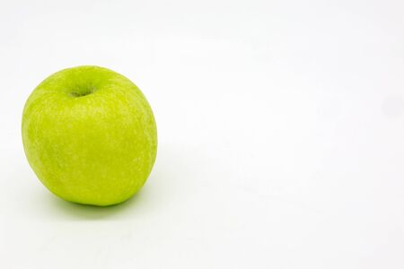 A studio photograph of a green apple against a white backgroundの写真素材