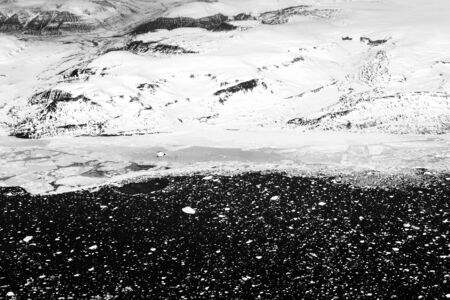 A black and  white photograph of a frozen landscape, viewed from an airplane windowの写真素材