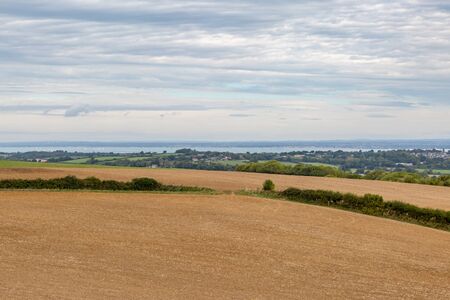 Looking out from a hilltop over farmland towards the coast, on the Isle of Wightの写真素材