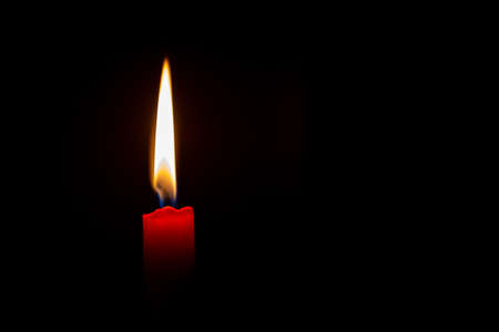 A lit red candle against a black backgroundの写真素材