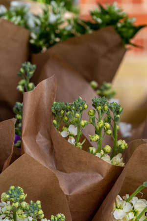 A display of flowers wrapped in brown paper at a florist shop, with a shallow depth of fieldの写真素材
