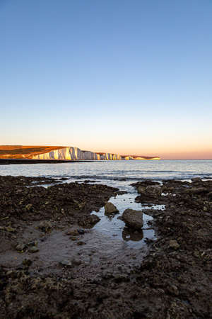 Sunset at the Seven Sisters Cliffs in Sussex, with the Rocky Beach at Hope Gap in the Foregroundの写真素材