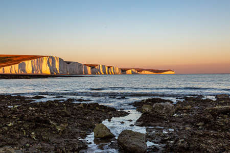 The rocky beach at Hope Gap on the Sussex coast, with a view of the Seven Sisters cliffs at sunsetの写真素材