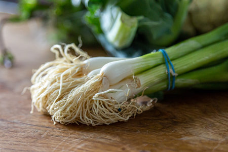 A bunch of spring onions on a chopping board, with a shallow depth of field