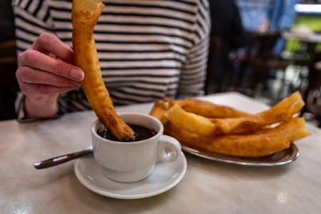 Churros being dipped into chocolateの写真素材