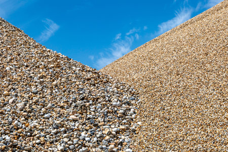 An abundance of pebbles sorted into small and large piles, with a blue sky overhead