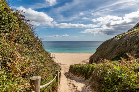 A view down a footpath to Porthcurno beach, with a blue sky overheadの写真素材